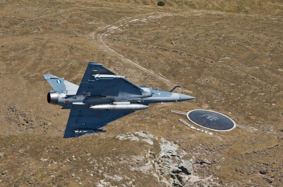 Ζεύγη Mirage 2000-5 της 331 Μοίρας “Θησέας” πραγματοποίησαν τιμητικές διελεύσεις πάνω από το μνημείο με την γιγαντιαία ασπίδα και το “Μολών Λαβέ” που στήθηκε στο νότιο ακρωτήριο του Αγίου Ευστρατίου για να θυμίζει την ηρωική πράξη του Θέρμιου Υποσμηναγού. Πηγή εικόνας: Πολεμική Αεροπορία