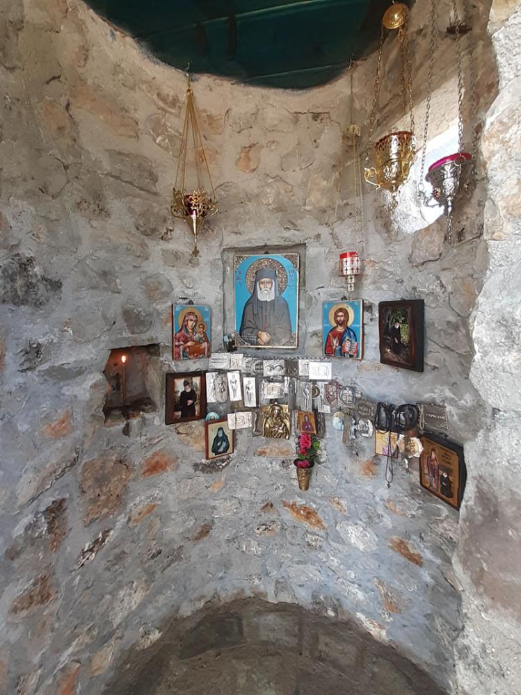  Στο εσωτερικό της δενδροκκλησιάς, υπάρχει η εικόνα του Αγίου Παϊσίου περιστοιχισμένη από τάματα πιστών και μια εσοχή 